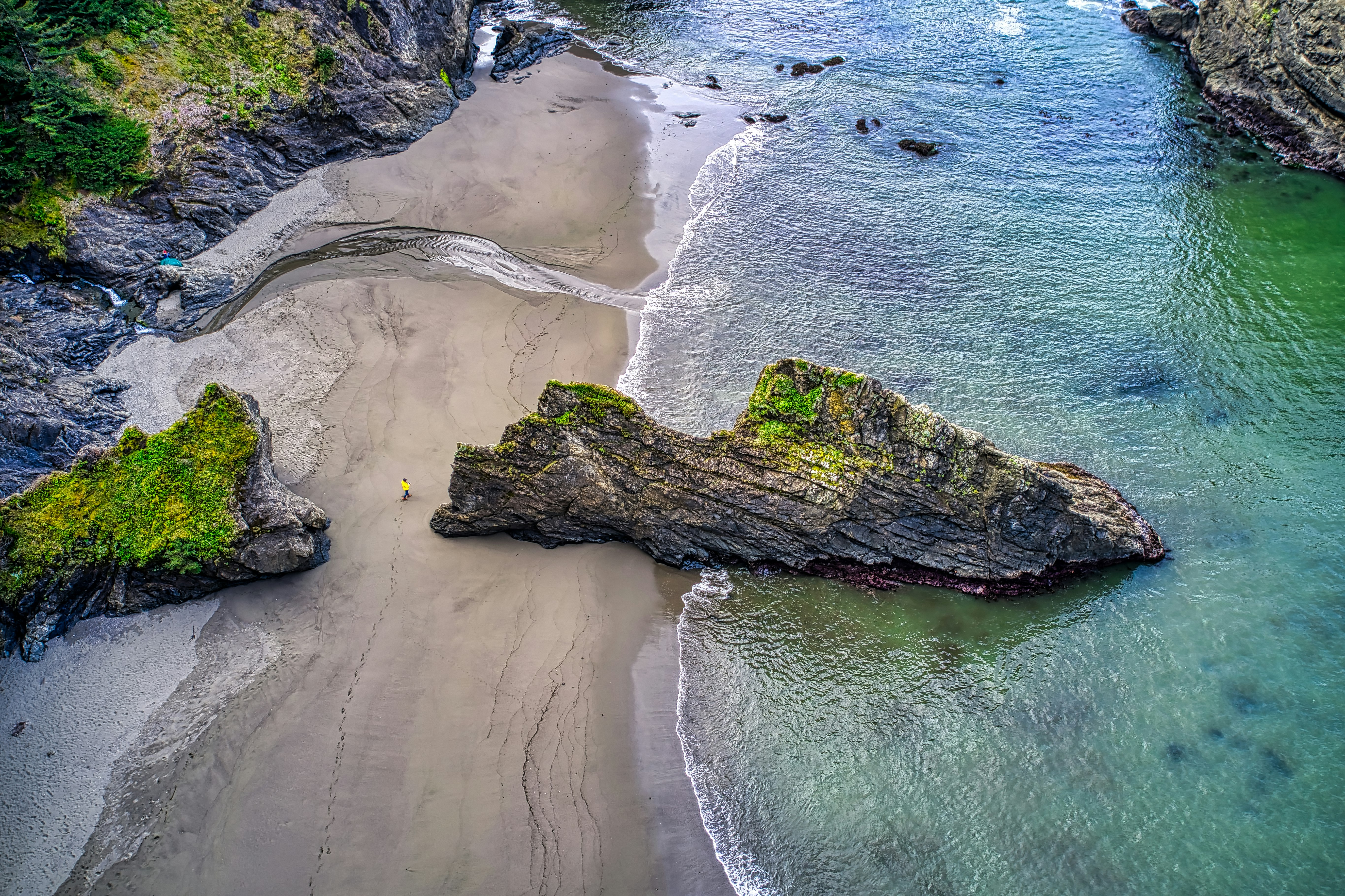 aerial view of green and brown rock formation on seashore during daytime